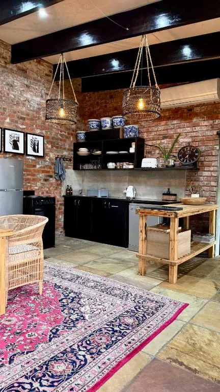 Modern kitchen with black cabinetry, wooden island, and exposed brick walls
