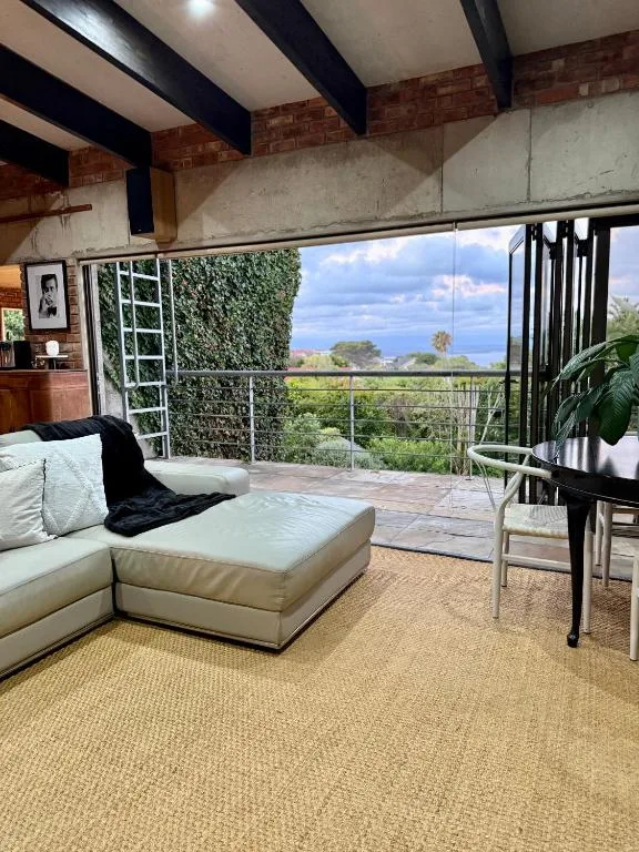 Modern loft lounge with cream sofa, mountain and garden views through large windows