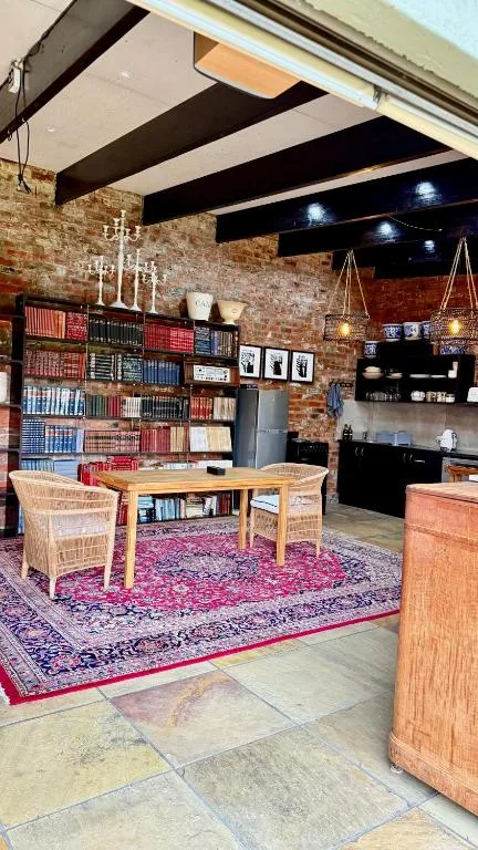 Open-plan living space with brick walls, wooden desk, comfortable seating, and bookshelves