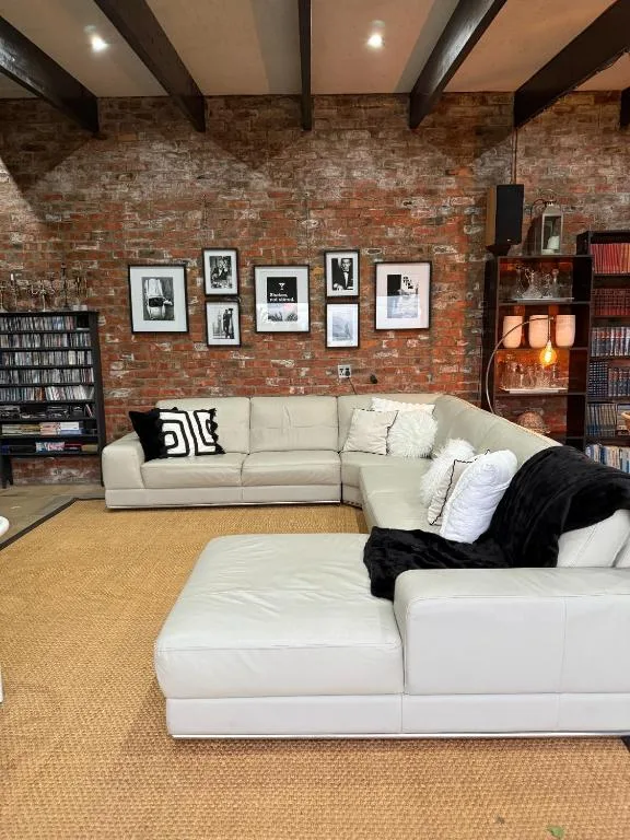 Modern lounge with cream sectional sofa, exposed brick wall, and framed artwork