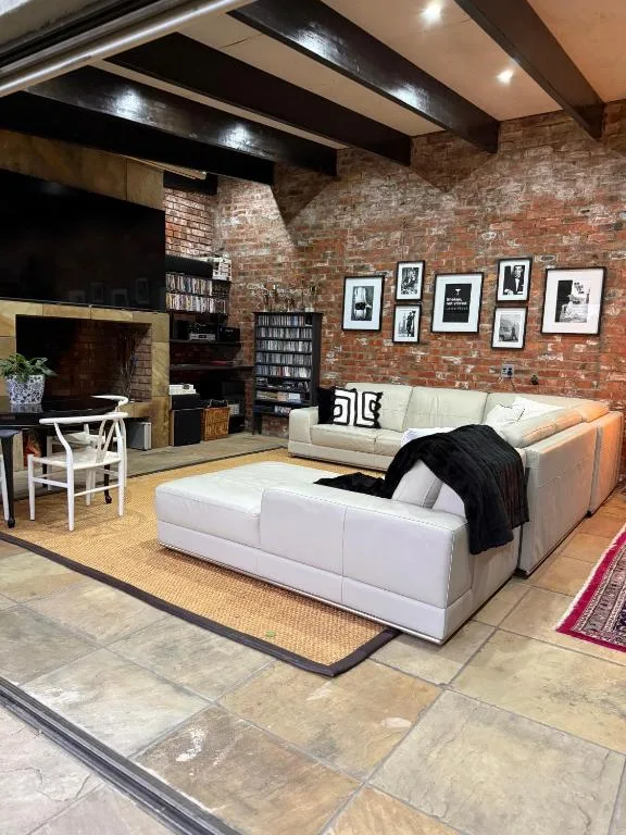 Modern open-plan lounge with white seating, exposed brick walls, and black beams