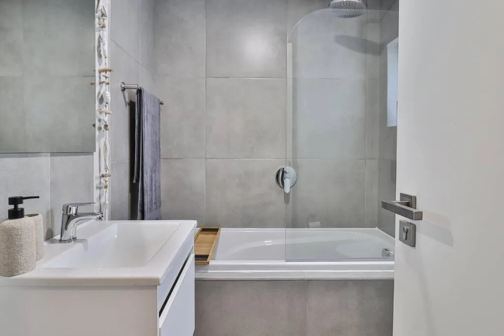 Modern bathroom with white basin sink and glass-enclosed shower enclosure