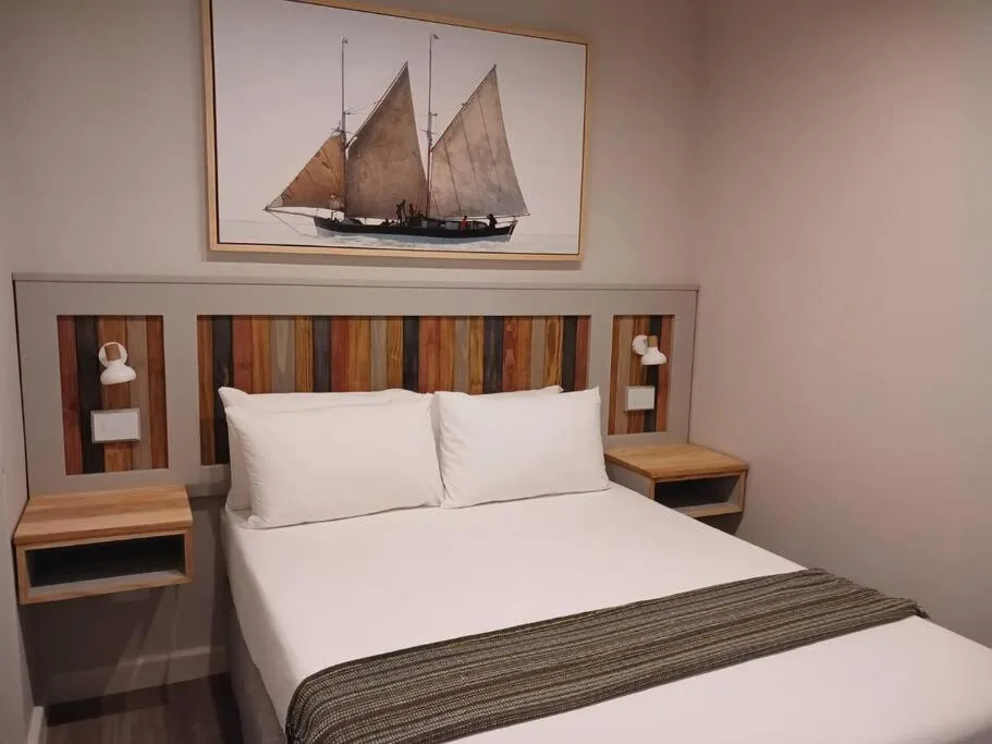 Bedroom with queen bed, wooden headboard, nautical sailboat artwork above