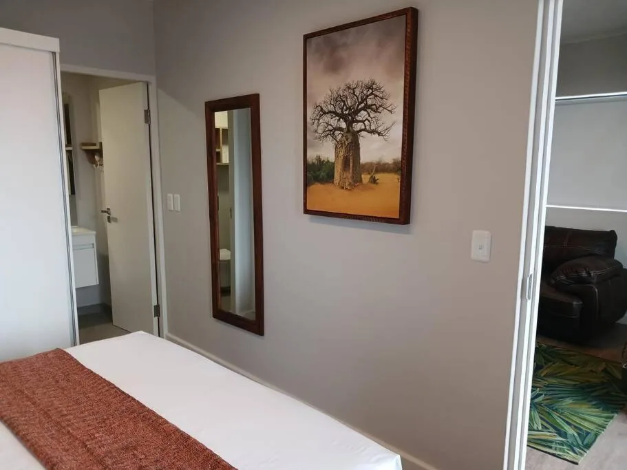 Bedroom with white bed, baobab tree artwork, and ensuite bathroom access