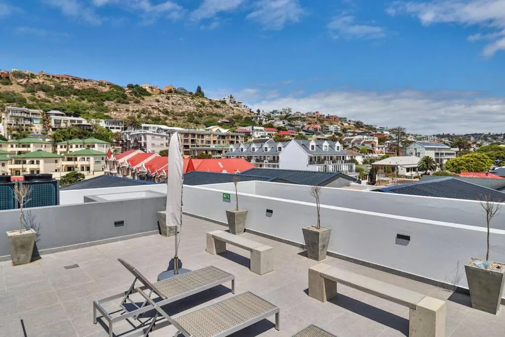 Rooftop terrace with loungers, umbrella, and panoramic coastal town views