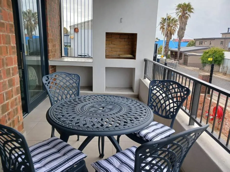 Outdoor balcony with round metal table and striped cushioned chairs