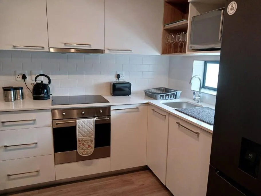 Modern white kitchen with stainless steel oven, sink, and integrated appliances