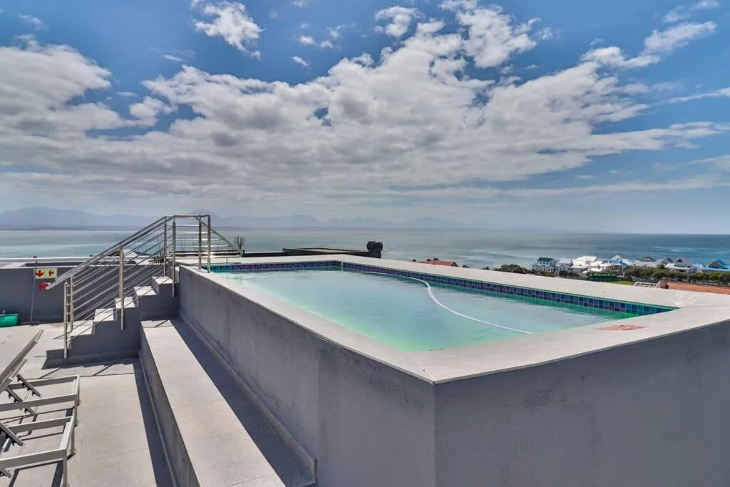 Rooftop swimming pool with ocean views and coastal landscape beyond