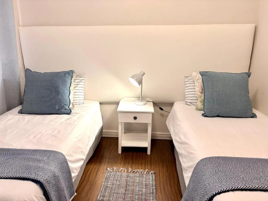 Twin bedroom with white headboard, blue pillows, and bedside lamp