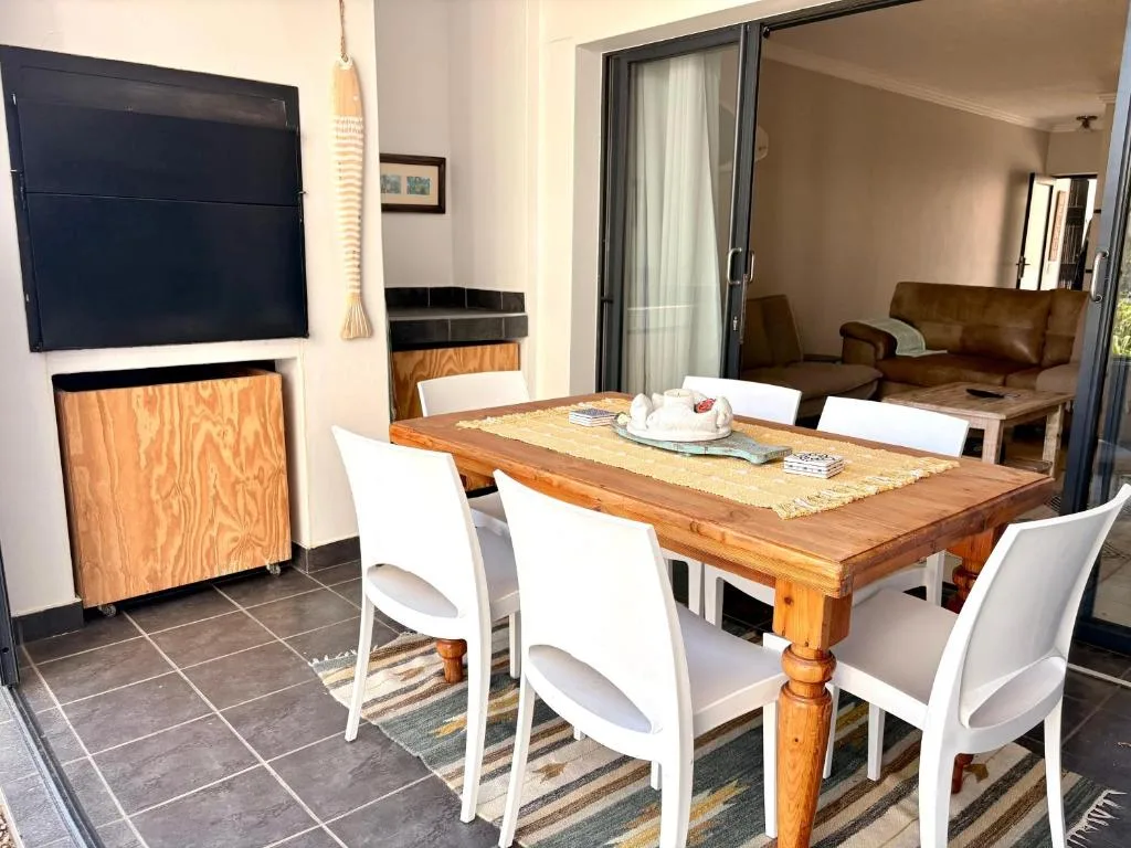 Wooden dining table with white chairs and open-plan living space beyond