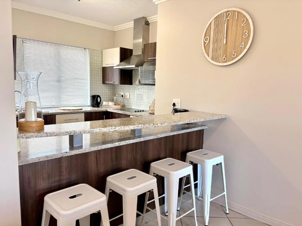 Modern kitchen with granite countertop, bar seating, and stainless steel appliances