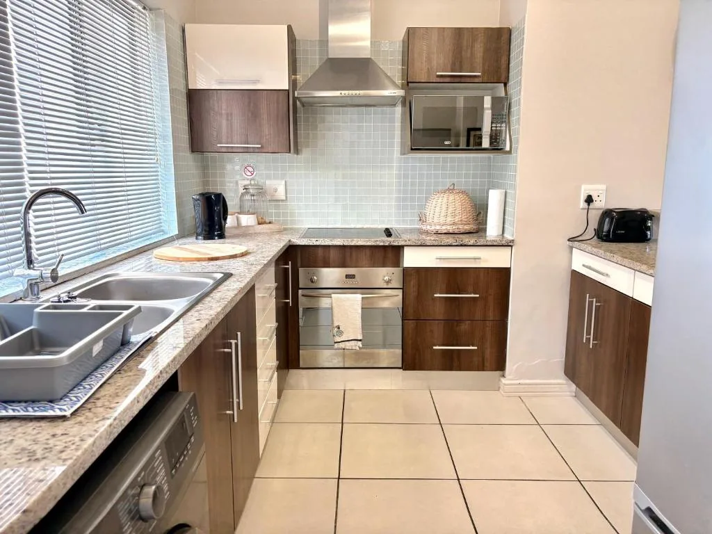 Modern kitchen with wood cabinetry, stainless steel appliances, and granite countertops