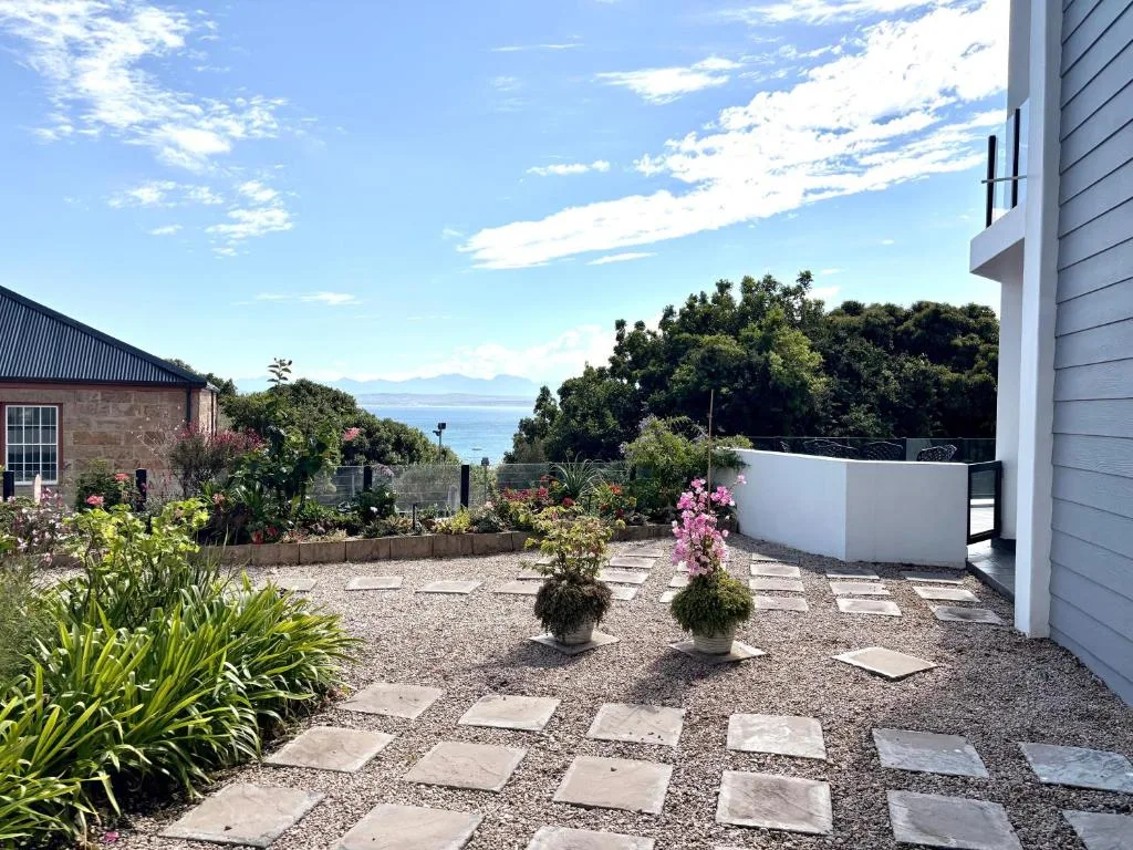 Coastal garden courtyard with sea glimpse through trees and mountains beyond