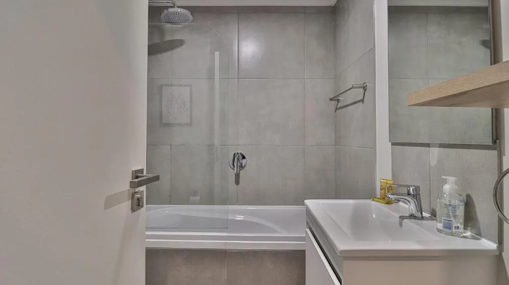 Modern bathroom with walk-in shower, vanity sink, and wooden shelving