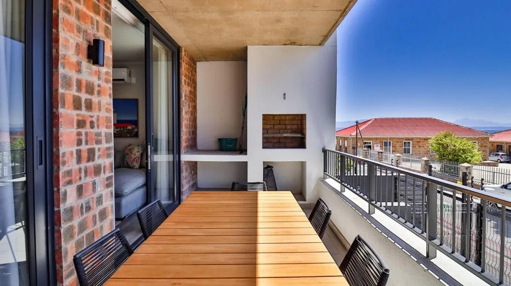 Sunny wooden deck with dining table and mountain views, modern railing