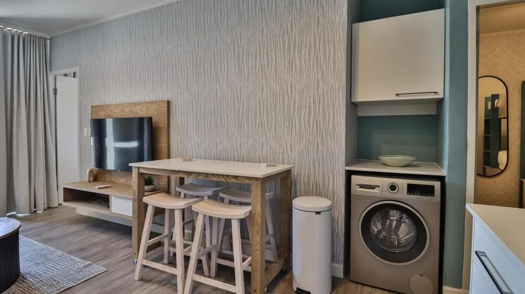 Modern open-plan apartment with kitchenette, bar seating, and laundry appliances