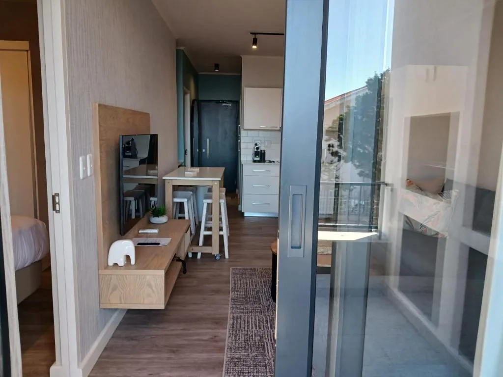 Modern apartment entryway with wooden desk, kitchen beyond, and glass balcony doors
