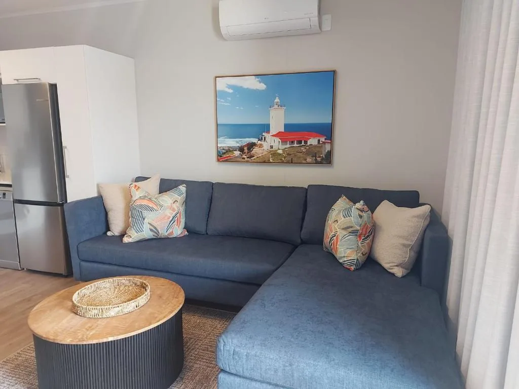 Modern living room with blue sectional sofa, wooden coffee table, and coastal artwork