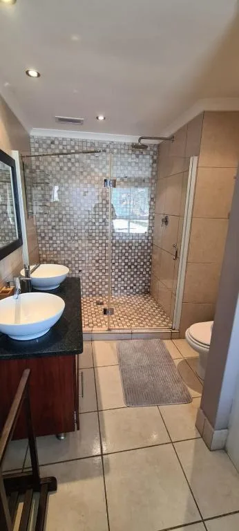 Modern bathroom with dual vanity, mosaic tile shower enclosure, and heated floor