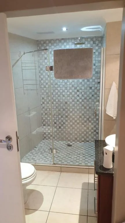 Modern bathroom with walk-in shower, checkered tile walls, and toilet