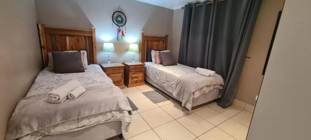 Twin bedroom with wooden beds, bedside lamps, and dreamcatcher wall decor