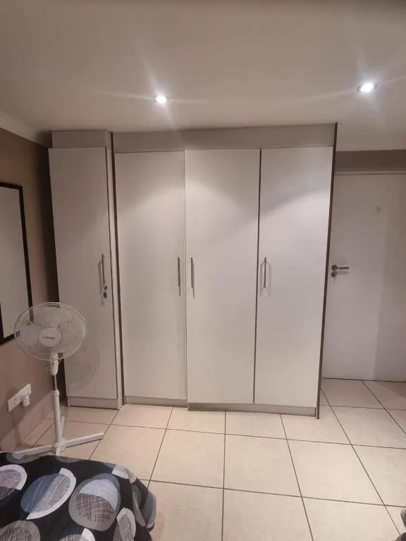 Modern bedroom with large white built-in wardrobe and tiled flooring