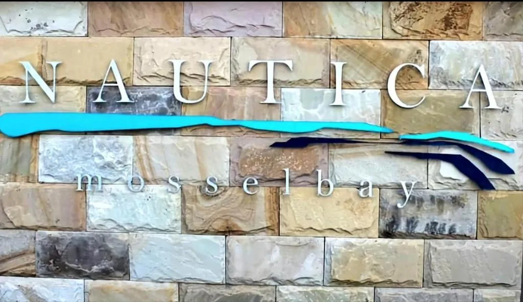 Nautica Mosselby property sign with decorative wave detail on stone wall