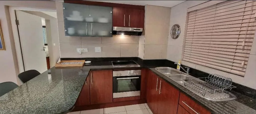 Modern kitchen with red cabinetry, stainless steel oven, and granite countertops