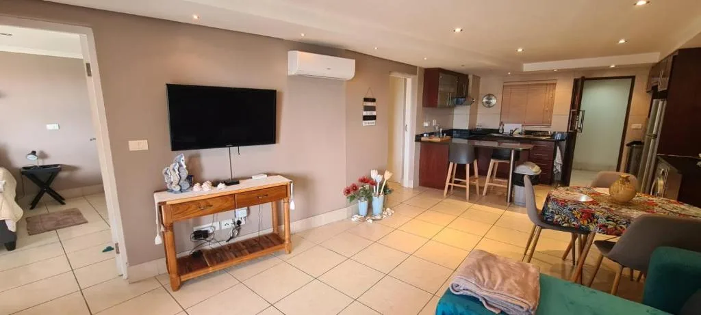 Open-plan lounge with wall-mounted TV and wooden entertainment console