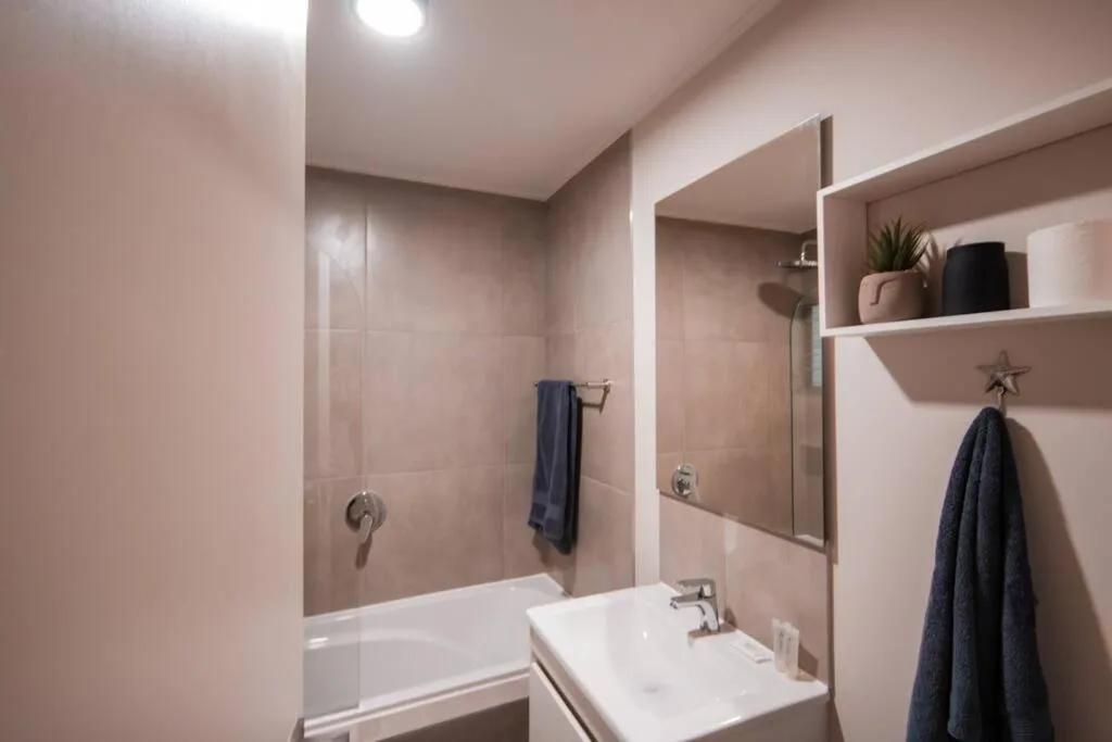 Modern bathroom with white sink, mirror, and tiled shower area