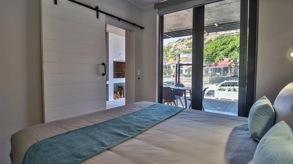 Modern bedroom with bed, sliding barn door, and deck access overlooking garden