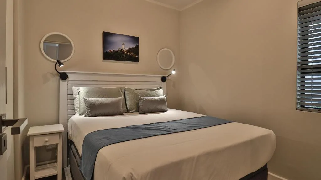 Modern bedroom with neatly made bed, neutral tones, and wall decor