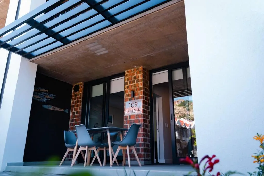 Modern covered patio with blue chairs and glass sliding doors entrance