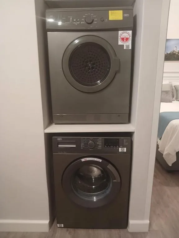 Stacked washer and dryer appliances in white alcove laundry space