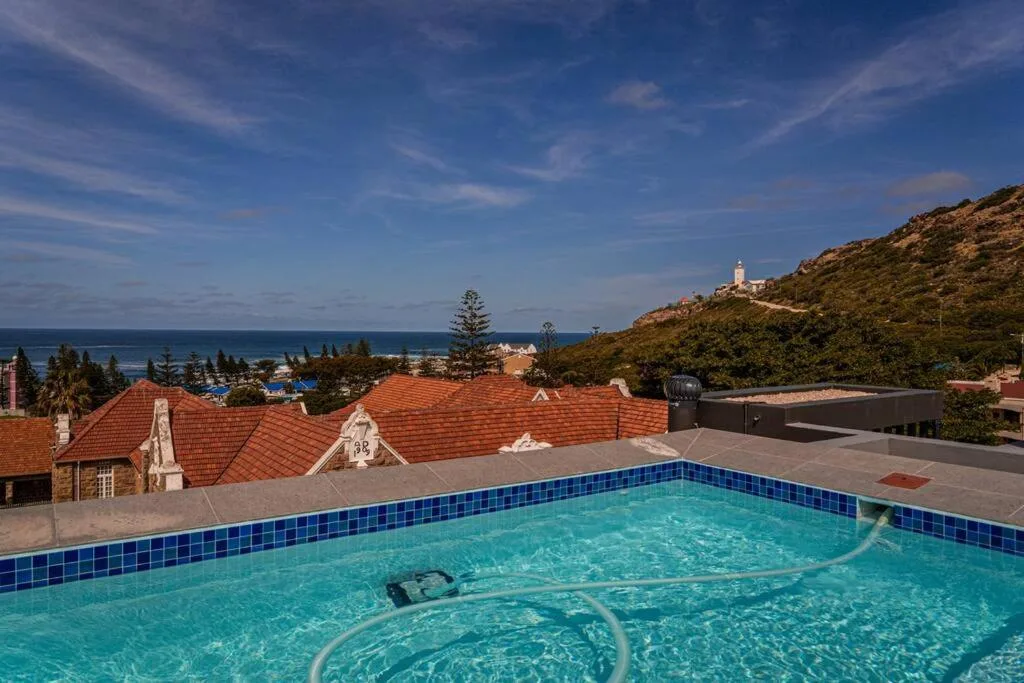 Swimming pool with ocean and coastal hills view in background