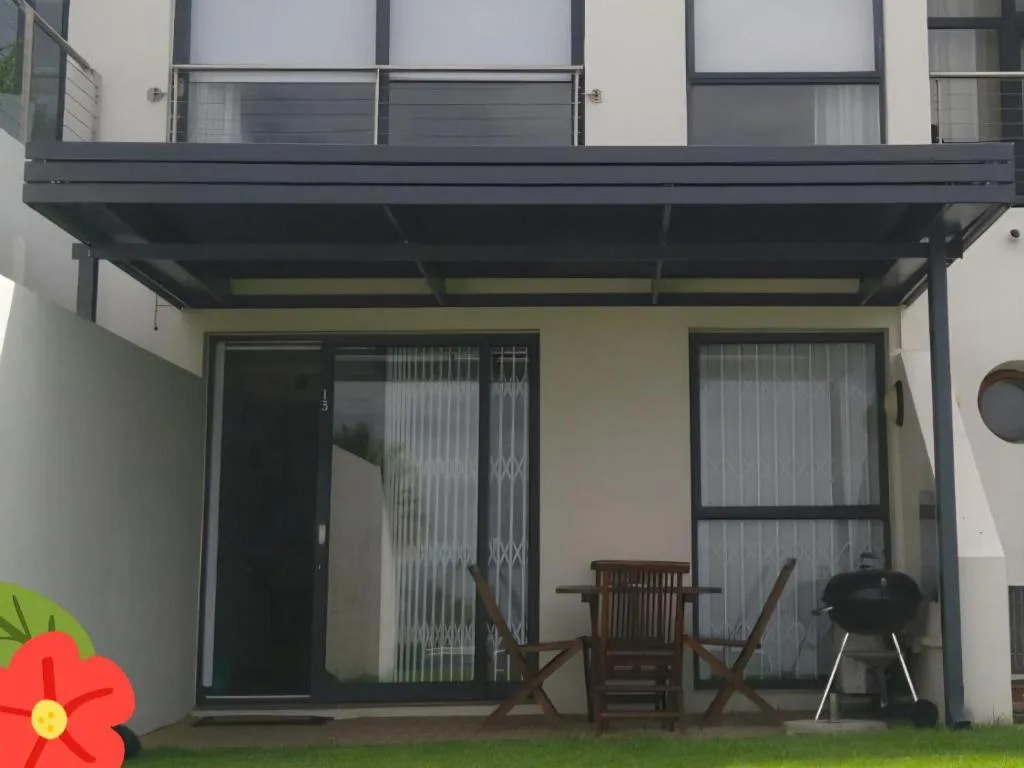 Covered patio with wooden chairs and braai grill, modern sliding doors