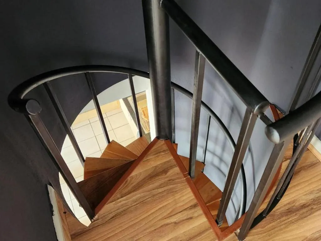 Modern spiral staircase with wooden steps and metal railing details