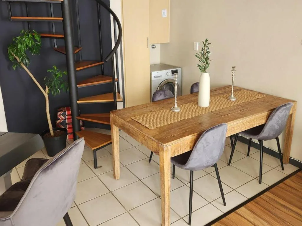 Wooden dining table with gray upholstered chairs in open-plan space