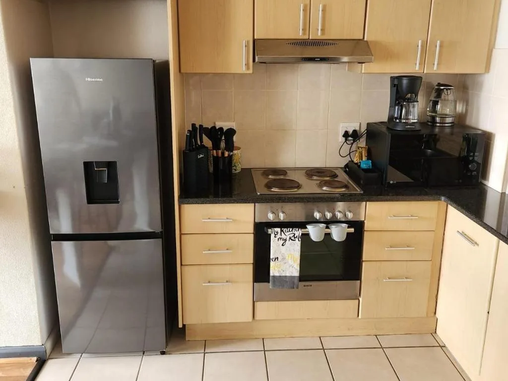 Modern kitchen with wooden cabinetry, stainless steel appliances, and black countertops