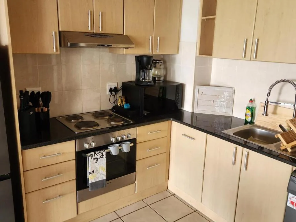 Modern kitchen with light wood cabinets, black countertop, electric oven and cooktop