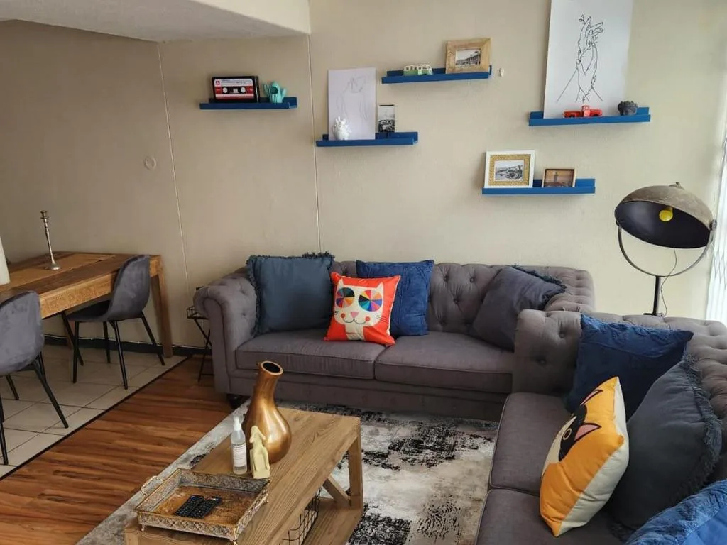Modern lounge with gray sectional sofa, colorful cushions, wooden coffee table