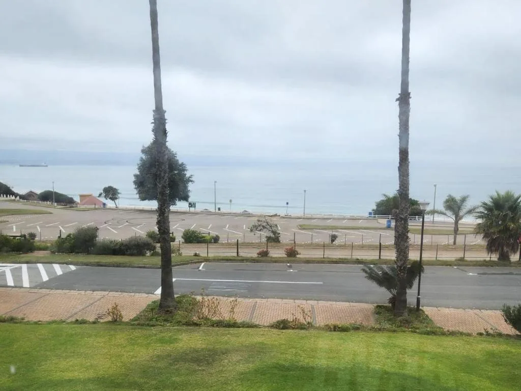 Sea view from property overlooking beach and coastal promenade with palm trees