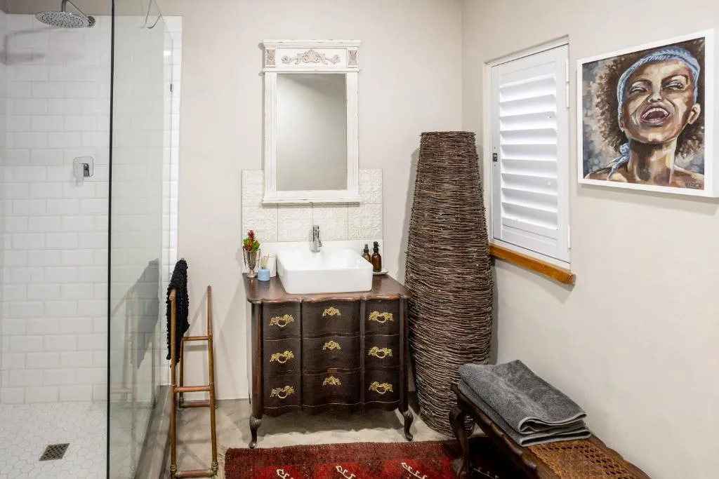 Modern bathroom with vintage vanity, white subway tiles, rainfall showerhead, and artistic wall decor