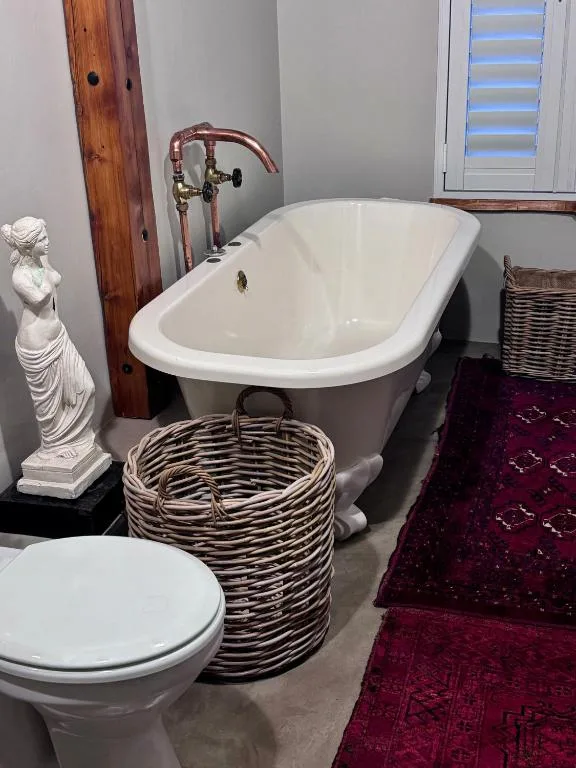 Freestanding bathtub with vintage faucet and decorative white statue beside it