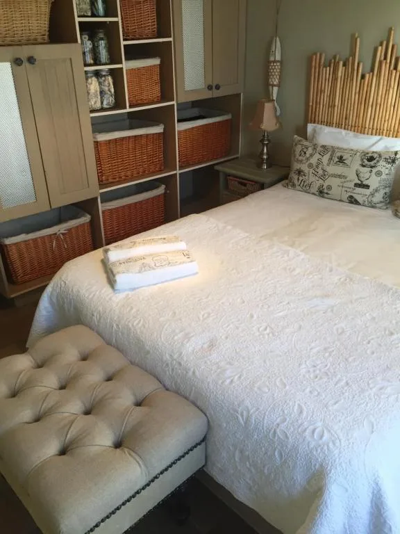 Spacious bedroom with white quilted bed and woven storage baskets