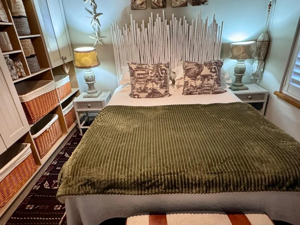 Bright bedroom with queen bed, decorative pillows, and woven storage units