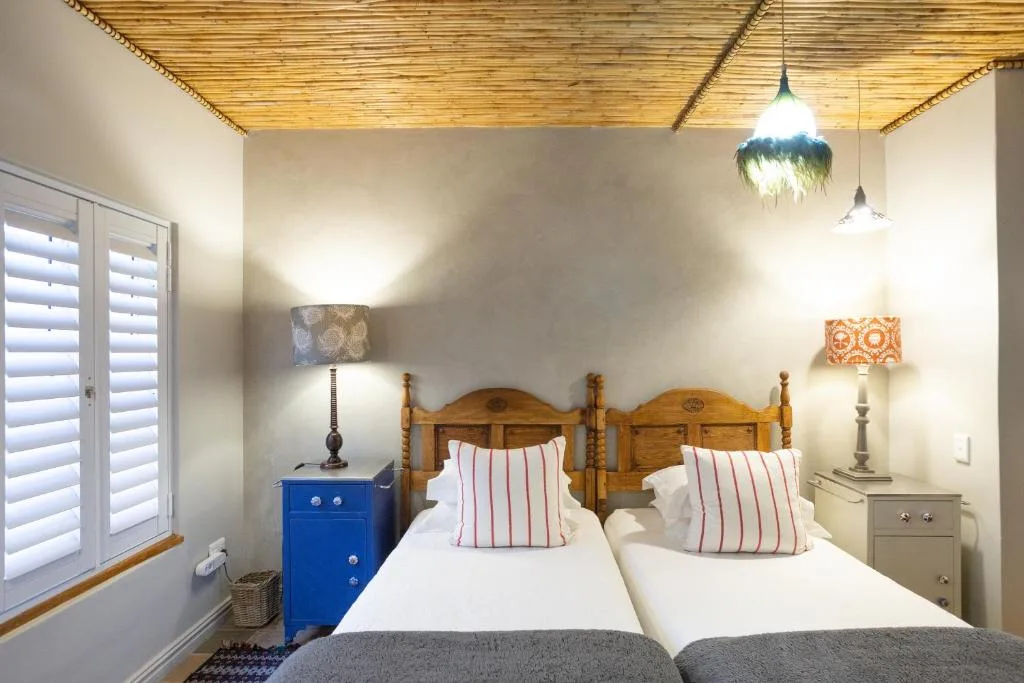 Twin beds with striped pillows, wooden headboards, pendant lights overhead.