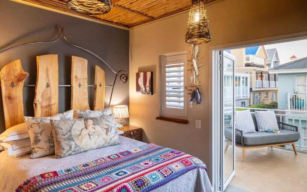 Warm bedroom with wooden headboard, colorful blanket, pendant lighting