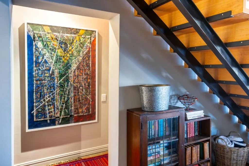 Framed colorful map artwork displayed above wooden bookshelf with decorative items
