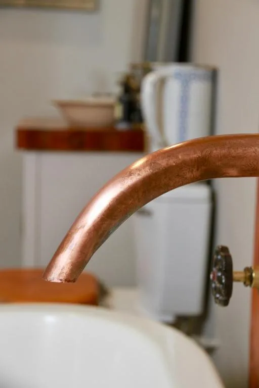 Close-up of wooden chair back with copper tap and decor in background